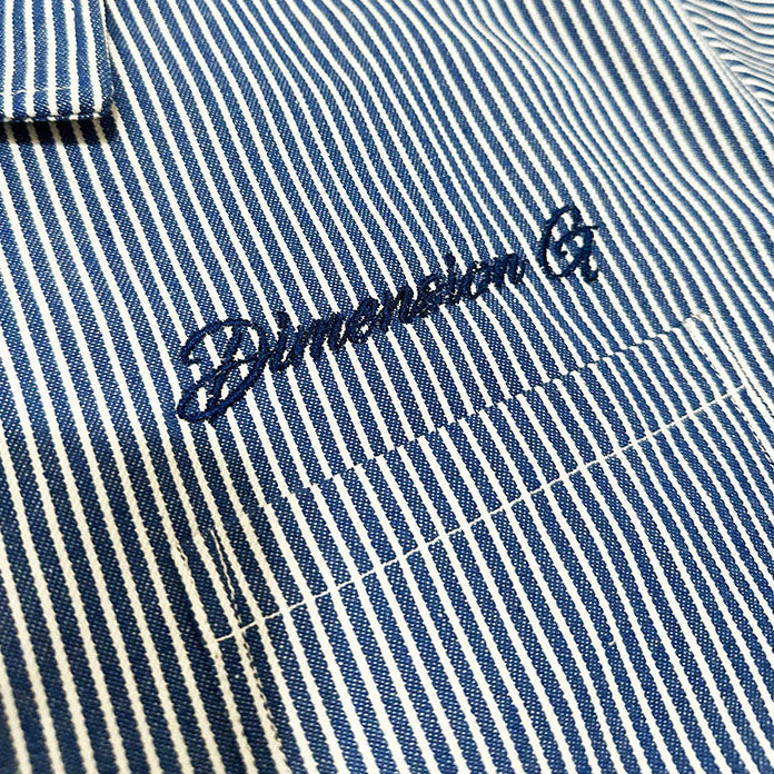 Close-up of a blue and white striped collared shirt with dark blue embroidered script on the chest pocket.